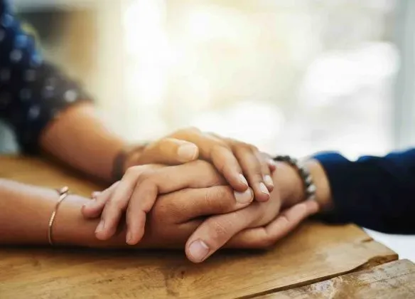 Soutien et réconfort lors d'un deuil avec deux mains serrées l'une contre l'autre.